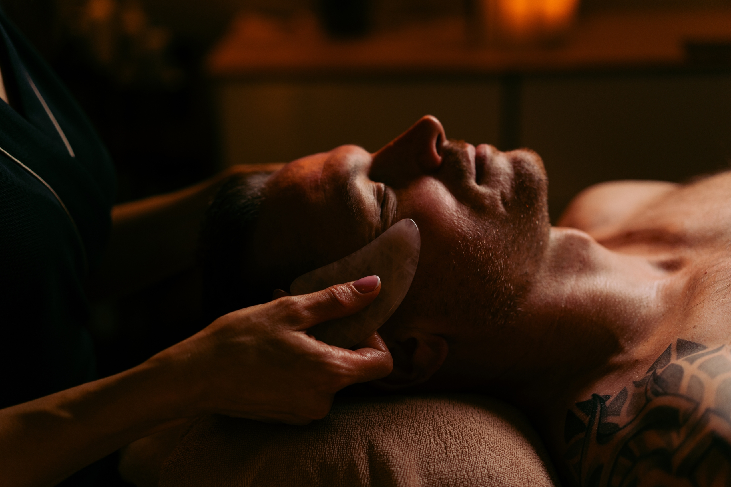 Glissements de la pierre Gua Sha le long des contours du visage pendant le soin facial chez Terramassa