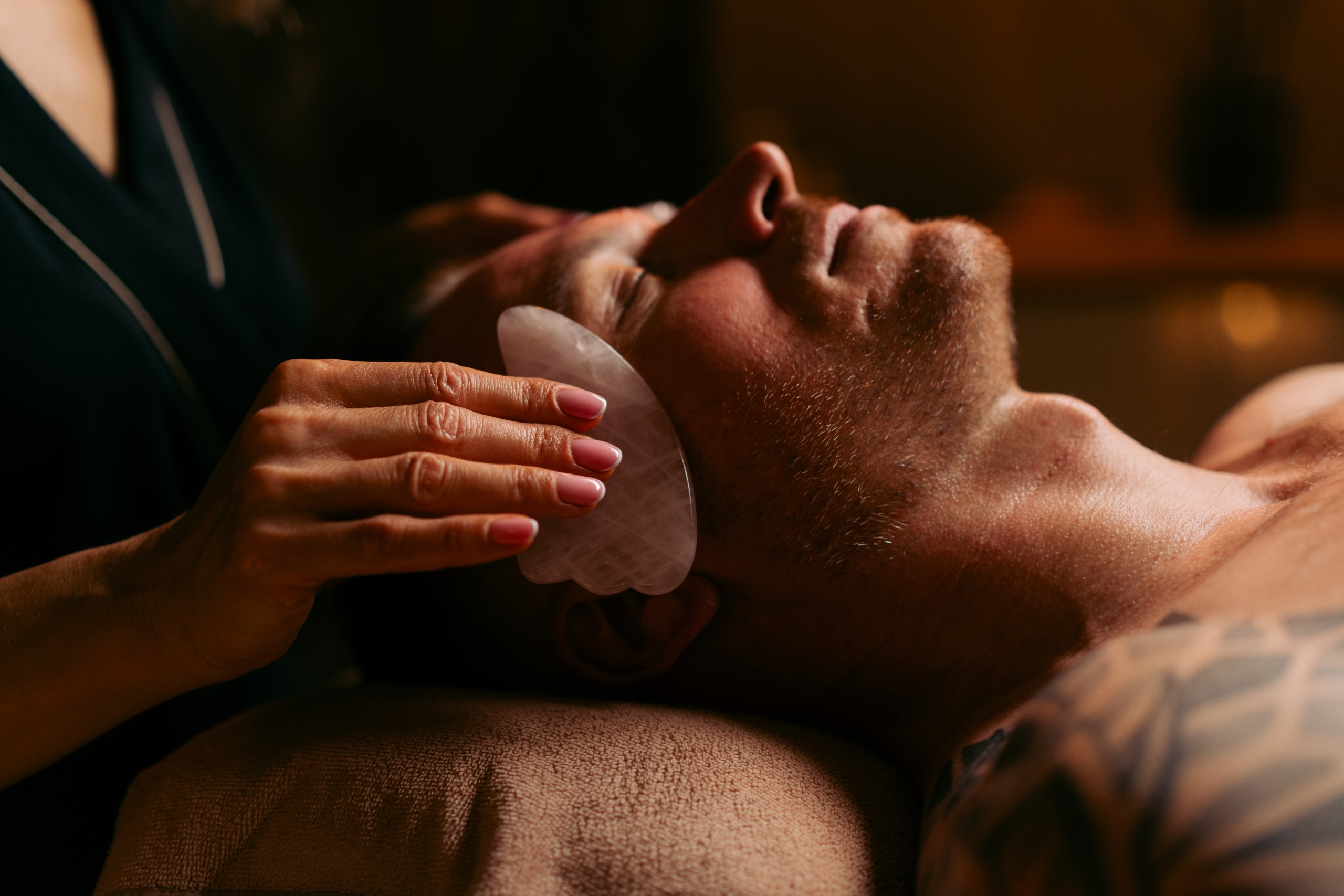 Facialiste utilisant une pierre Gua Sha sur le visage lors d’un soin facial chez Terramassa près de Metz